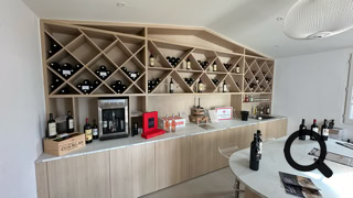 Agencement sur mesure pour cave à vin avec casiers à bouteilles, rangements intégrés et plan de travail, réalisé par Graille Menuiserie.